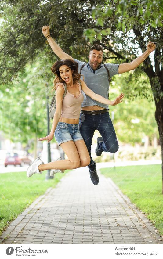 Unbeschwertes Paar springt im Park glücklich Glück glücklich sein glücklichsein Parkanlagen Parks Pärchen Paare Partnerschaft springen hüpfen Sorglos Mensch
