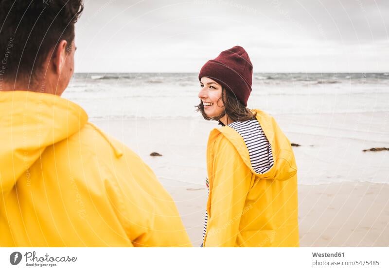 Junge Frau in gelben Regenjacken und Strandspaziergang, Bretagne, Frankreich Mützen freuen Frohsinn Fröhlichkeit Heiterkeit Glück glücklich sein glücklichsein