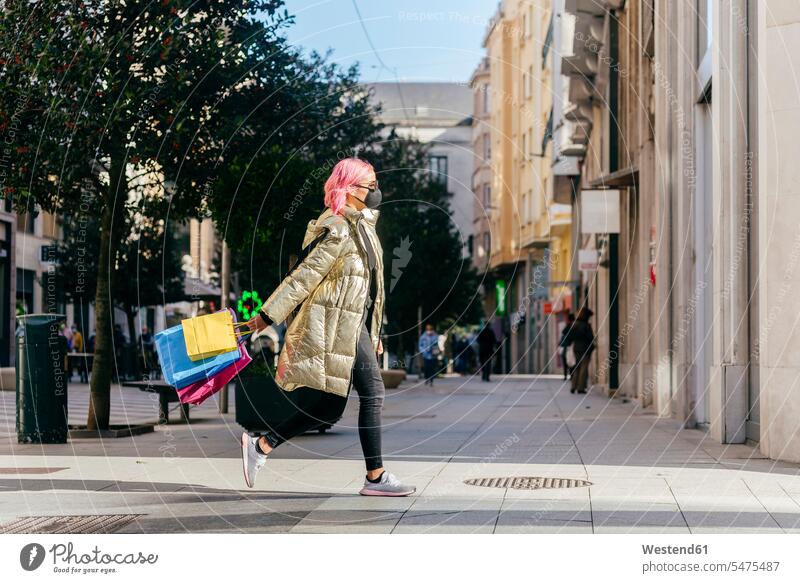 Frau mit Gesichtsmaske läuft mit Einkaufstüten auf Gehweg in Stadt Farbaufnahme Farbe Farbfoto Farbphoto Außenaufnahme außen draußen im Freien Tag