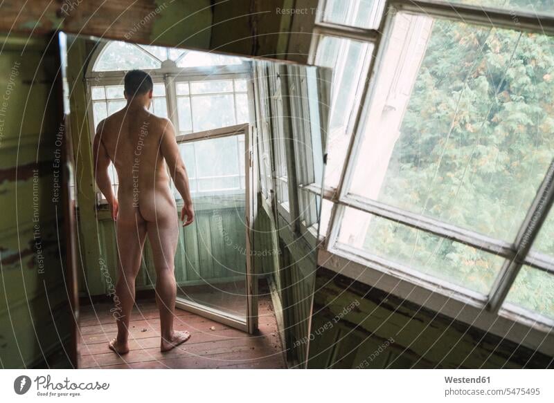 Spiegelbild eines nackten Mannes, der am Fenster eines verlassenen Hauses steht Häuser Haeuser unbekleidet nacktes nackter Nacktheit Männer männlich stehen