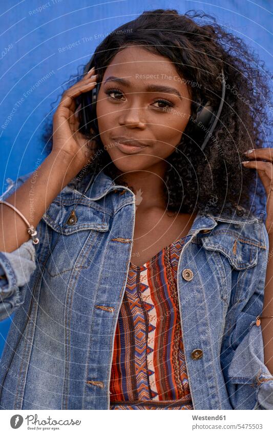 Porträt einer jungen Frau, die mit Kopfhörern Musik hört Leute Menschen People Person Personen Afrikanisch Afrikanische Abstammung dunkelhäutig Farbige Farbiger