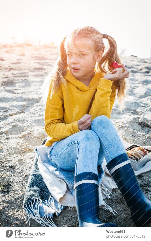 Porträt von Mädchen mit Zöpfen sitzen am Strand im Herbst essen einen Apfel Äpfel Aepfel Portrait Porträts Portraits Beach Straende Strände Beaches weiblich