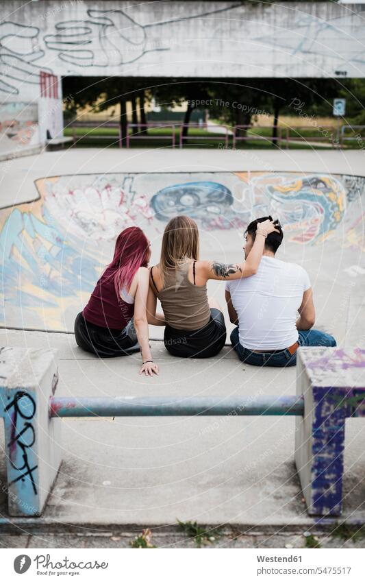 Rückansicht von Freunden, die im Skatepark sitzen sitzend sitzt Skateboardpark Skateboard-Park Skateboard Park Skaterplatz Parkanlagen Parks Freundschaft
