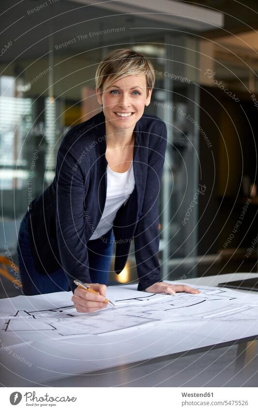 Porträt einer lächelnden Frau, die im Büro an einem Bauplan arbeitet Job Berufe Berufstätigkeit Beschäftigung Jobs geschäftlich Geschäftsleben Geschäftswelt