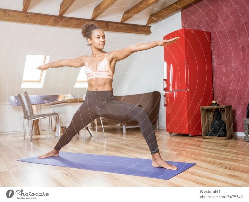 Junge Frau praktiziert Yoga auf dem Dachboden Übung Uebung Übungen Uebungen Mansarde Mansarden weiblich Frauen Zimmer Raum Räume Erwachsener erwachsen Mensch