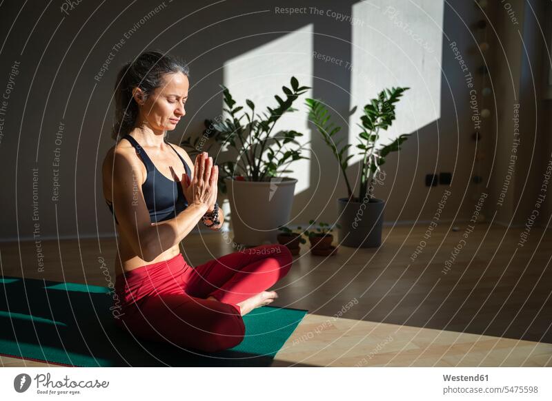 Weibliche Yoga-Lehrer mit geschlossenen Augen tun Gebetspose zu Hause auf sonnigen Tag Farbaufnahme Farbe Farbfoto Farbphoto Innenaufnahme Innenaufnahmen innen