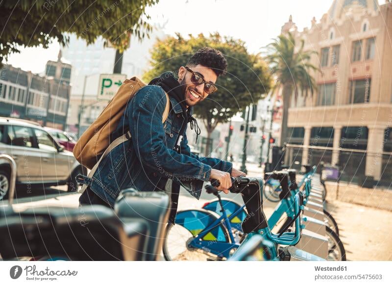 Stilvoller junger Mann auf der Straße mit einem Mietfahrrad Männer männlich Fahrrad Bikes Fahrräder Räder Rad Style stylisch Erwachsener erwachsen Mensch