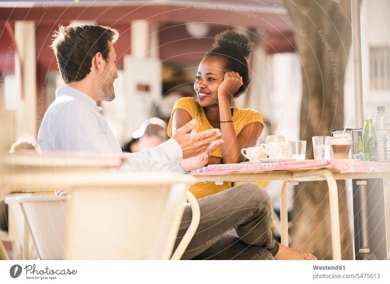 Glückliches junges Paar unterhält sich in einem Straßencafé Gläser Trinkglas Trinkgläser Tische Flirt sitzend sitzt reden Jahreszeiten sommerlich Sommerzeit