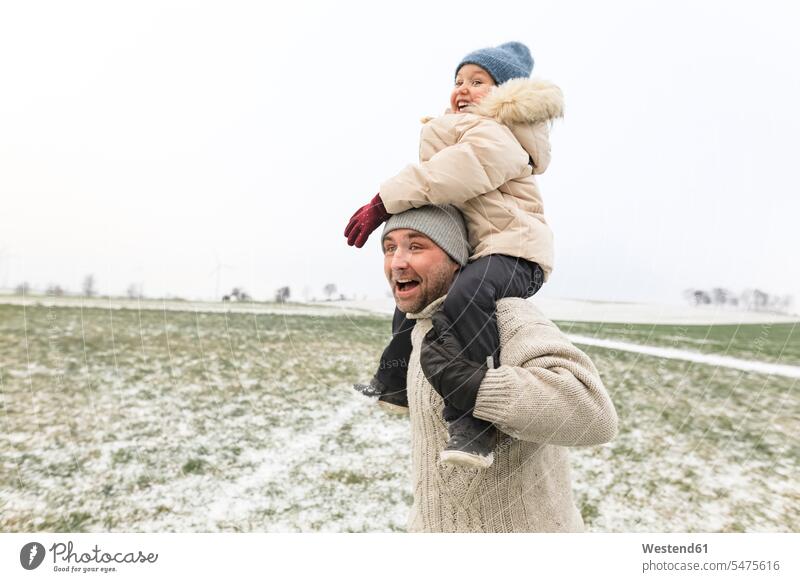Verspielter Vater trägt Tochter Huckepack in Winterlandschaft verspielt spielerisch winterlich Winterzeit tragen transportieren Töchter Winterlandschaften Papas