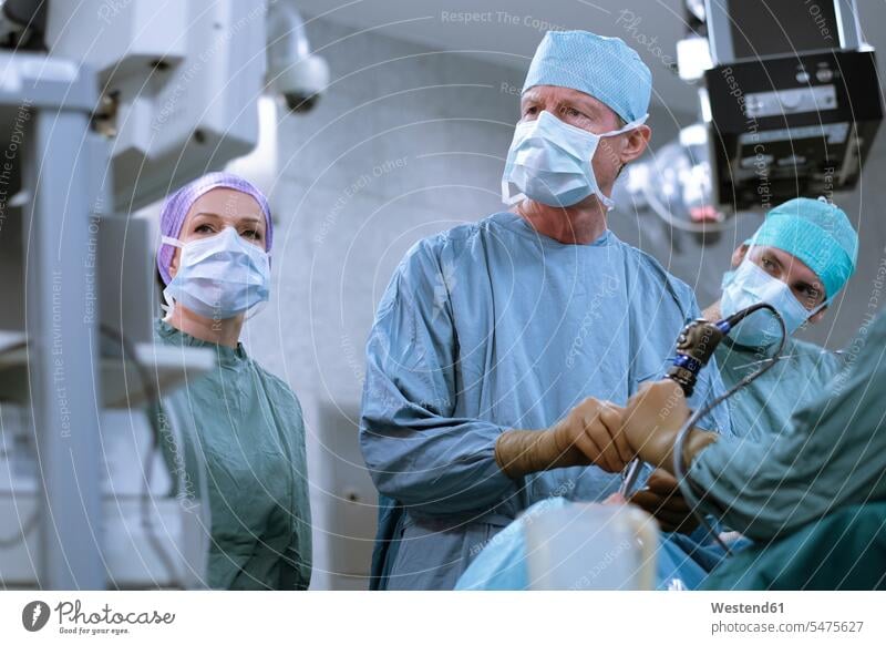 Team von Neurochirurgen in Kitteln während einer Operation Chirurg Chirurgen Krankenhaus Kliniken Krankenhäuser Krankenhaeuser Operationskittel OP Operationen