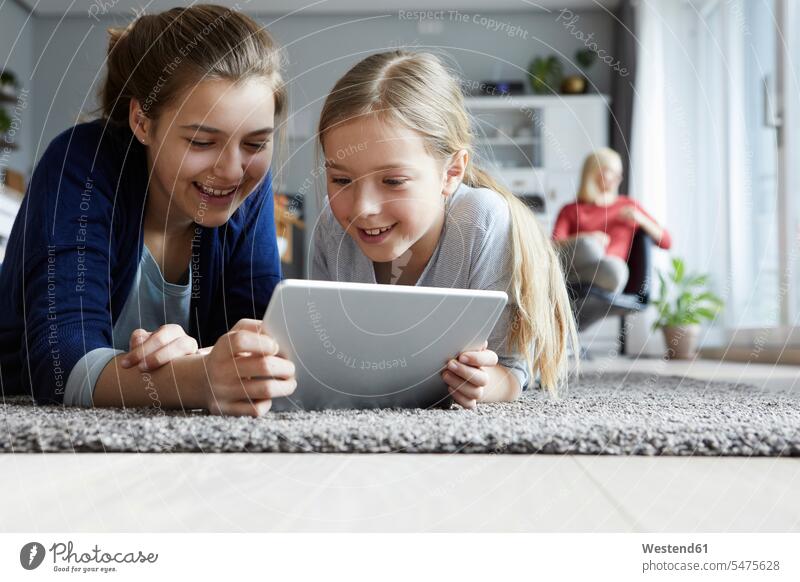 Teo-Schwestern liegen auf dem Boden und spielen mit dem digitalen Tablett lernen Tablet Computer Tablet-PC Tablet PC iPad Tablet-Computer Fußboden Fußboeden