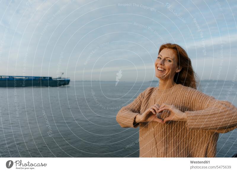Deutschland, Hamburg, glückliche Frau am Elbufer Glück glücklich sein glücklichsein weiblich Frauen Schiff Schiffe lächeln Flussufer Erwachsener erwachsen