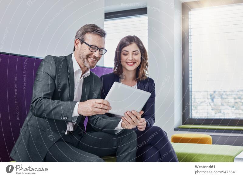 Lächelnder Geschäftsmann und Geschäftsfrau benutzen gemeinsam Tablet in Büro-Lounge Lounges Tablet Computer Tablet-PC Tablet PC iPad Tablet-Computer