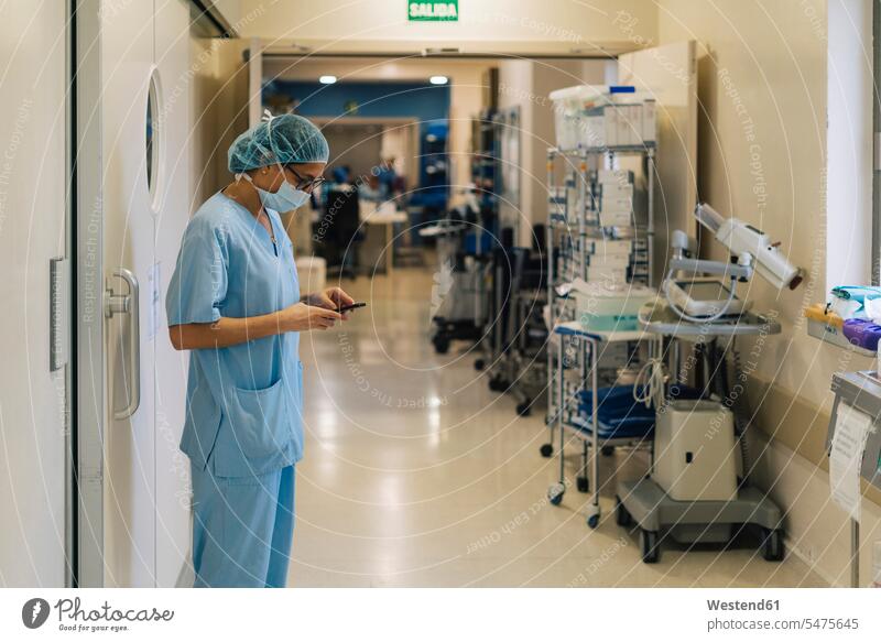 Weiblicher Arzt mit Smartphone im Krankenhaus, Vorbereitung für die Operation Beruf Berufstätigkeit Berufe Beschäftigung Jobs vorbereiten Telekommunikation