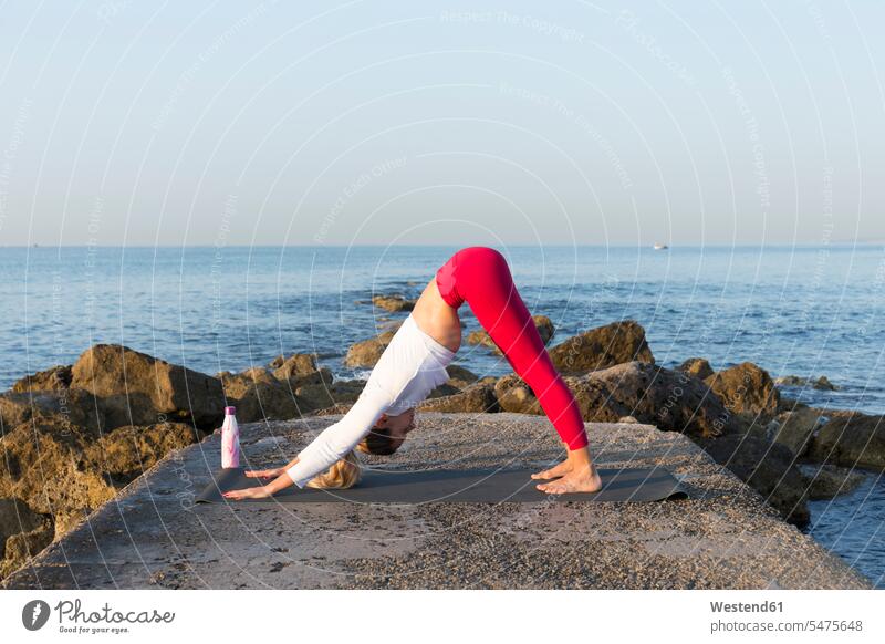 Junge Frau übt Yoga am Strand, macht nach unten gerichteten Hund ausüben trainieren Übung früh Frühe Morgen anpassungsfähig Anpassungsfähigkeit flexibel kräftig