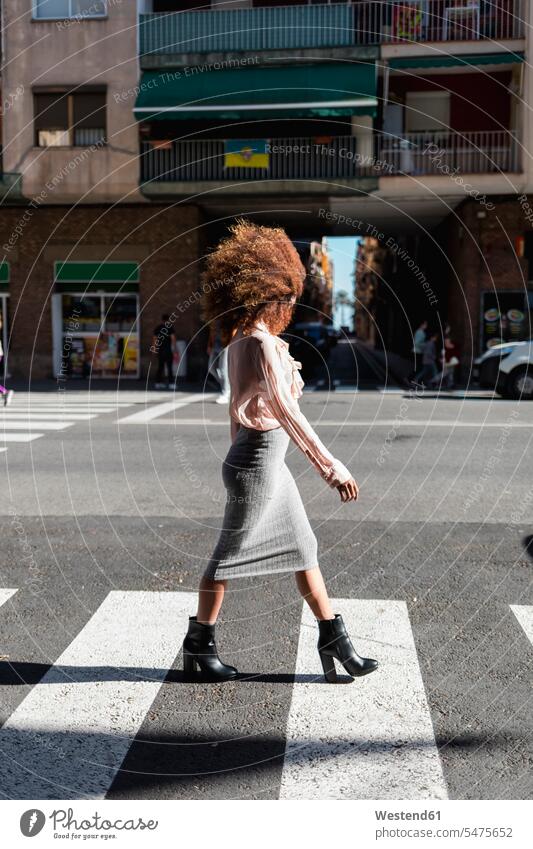 Junge Frau mit Afrofrisur beim Überqueren der Straße in der Stadt Strassen Straßen überqueren Barcelona Gesicht verdeckt verdecktes Gesicht