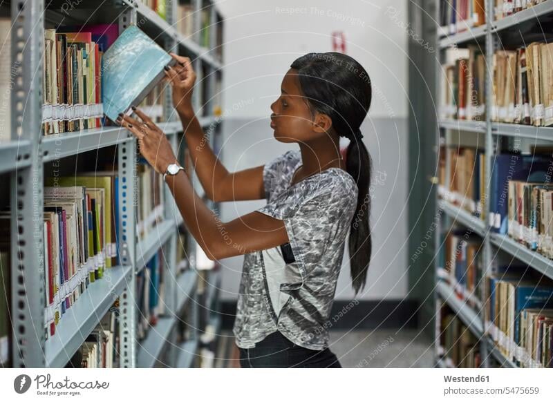 Junge Frau prüft die Bücher in den Regalen der Nationalbibliothek, Maputo, Mosambik Leute Menschen People Person Personen Afrikanisch Afrikanische Abstammung