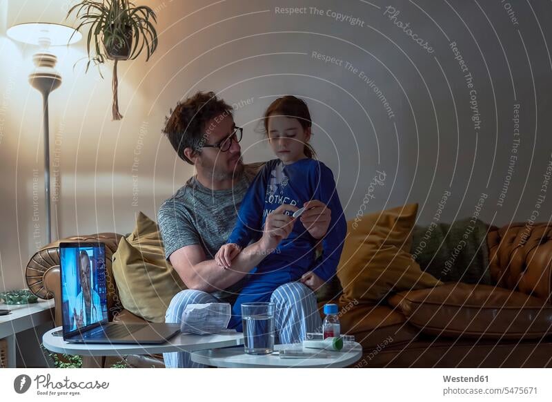 Mann hält Thermometer, während er mit seiner kranken Tochter während eines Videoanrufs zu Hause sitzt Farbaufnahme Farbe Farbfoto Farbphoto Innenausstattung