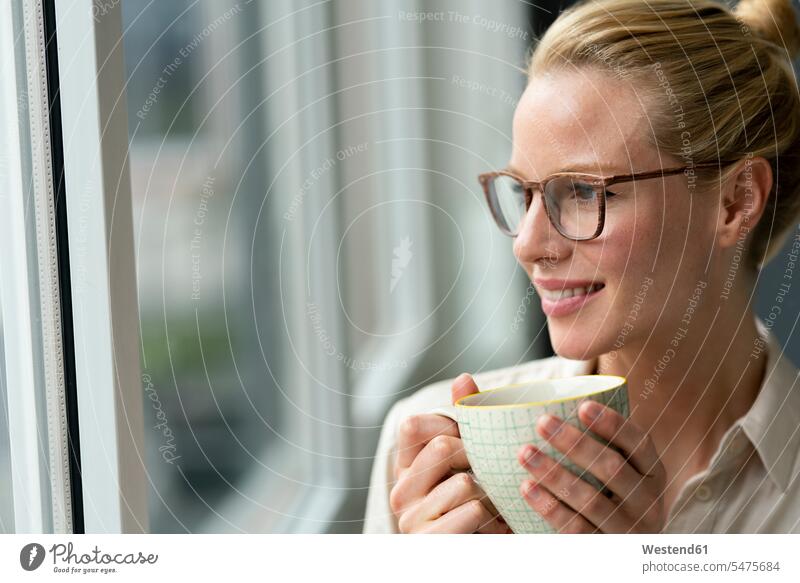 Junge Geschäftsfrau mit einer Tasse Kaffee, die aus dem Fenster schaut Job Berufe Berufstätigkeit Beschäftigung Jobs geschäftlich Geschäftsleben Geschäftswelt