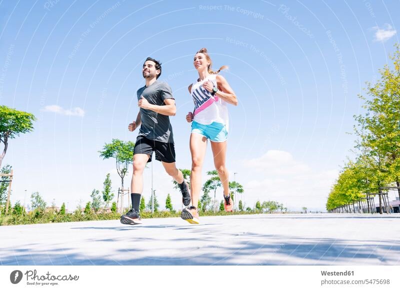 Mittelgroßes erwachsenes Paar rennt am sonnigen Tag auf der Straße gegen blauen Himmel Farbaufnahme Farbe Farbfoto Farbphoto Spanien Außenaufnahme außen draußen