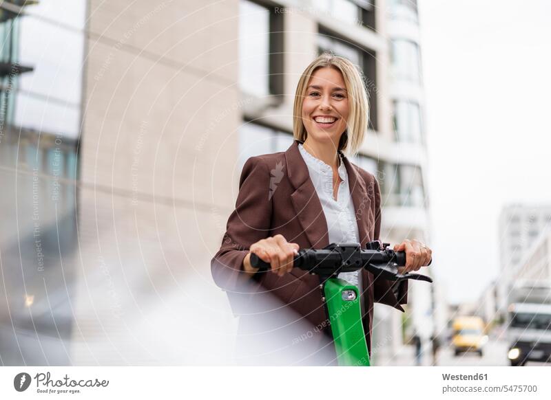 Porträt einer glücklichen jungen Geschäftsfrau mit E-Scooter in der Stadt geschäftlich Geschäftsleben Geschäftswelt Geschäftsperson Geschäftspersonen