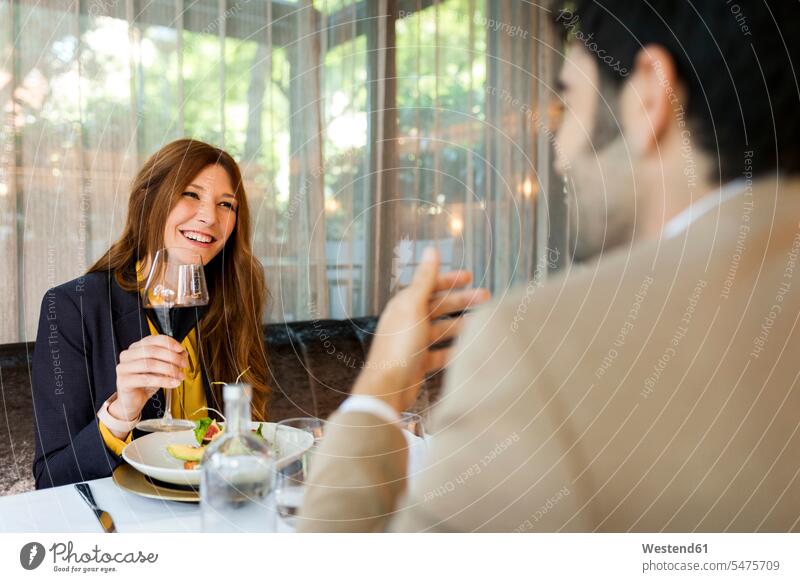 Lächelnde Frau mit Glas Rotwein schaut Mann in einem Restaurant an lächeln Lokal Speiserestaurant Lokale Speiselokale Restaurants Speiserestaurants Paar Pärchen