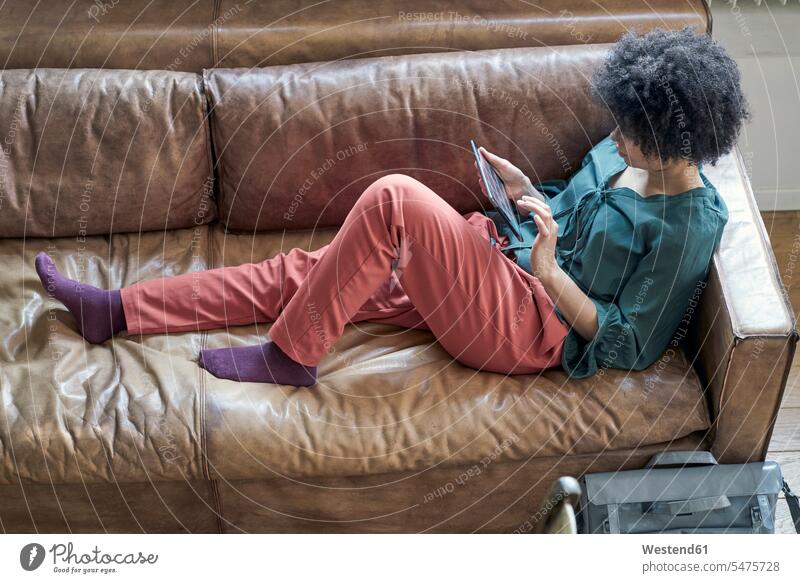 Junge Frau liegt mit Tablette auf Couch weiblich Frauen liegen liegend Sofa Couches Liege Sofas Tablet Computer Tablet-PC Tablet PC iPad Tablet-Computer