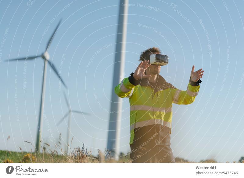 Ingenieur steht mit VR-Brille auf einem Feld in einem Windpark Brillen virtuell Virtualität stehen stehend Felder Ingenieure Windenergieanlage WEA WEAs