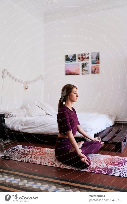 Junge brünette Frau übt Yoga im Studentenwohnheim Betten entspannen relaxen entspanntheit relaxt bescheiden Bescheidenheit genügsam lilafarben violett daheim