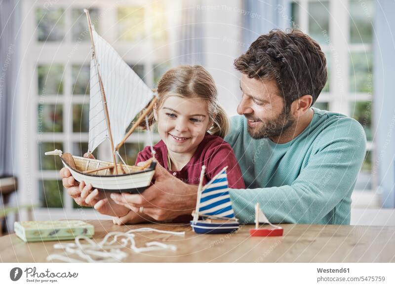 Glückliche Vater und Tochter spielen zu Hause mit dem Modellboot Spielzeugboot Töchter Papas Väter Vati Vatis Papis Zuhause daheim glücklich glücklich sein