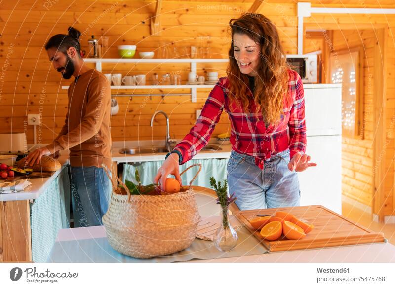 Frau mit Freund in einer Holzhütte bei der Zubereitung von Orangen Touristen Koerbe Körbe freuen geniessen Genuss Glück glücklich sein glücklichsein bescheiden