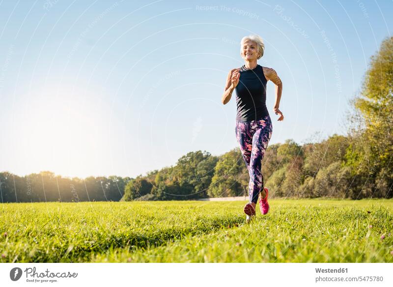 Ältere Frau läuft auf ländlicher Wiese laufen rennen Wiesen auf dem Land auf dem Lande weiblich Frauen Seniorin älter Seniorinnen alt Erwachsener erwachsen