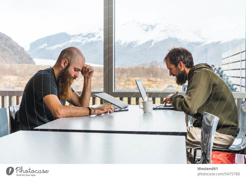 Island, zwei Hipster, die in einem Café am Tisch sitzen Tische Cafe Kaffeehaus Bistro Cafes Kaffeehäuser sitzend sitzt Blick nach unten Internet WLan