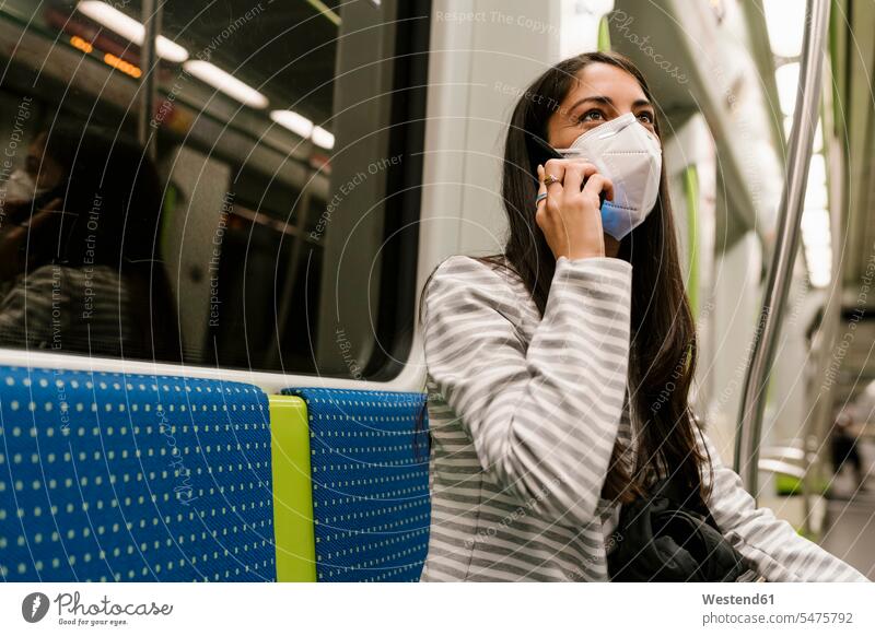 Frau schaut weg, während sie mit einem Smartphone im U-Bahn-Zug spricht Farbaufnahme Farbe Farbfoto Farbphoto Spanien sitzen sitzend sitzt Infektion