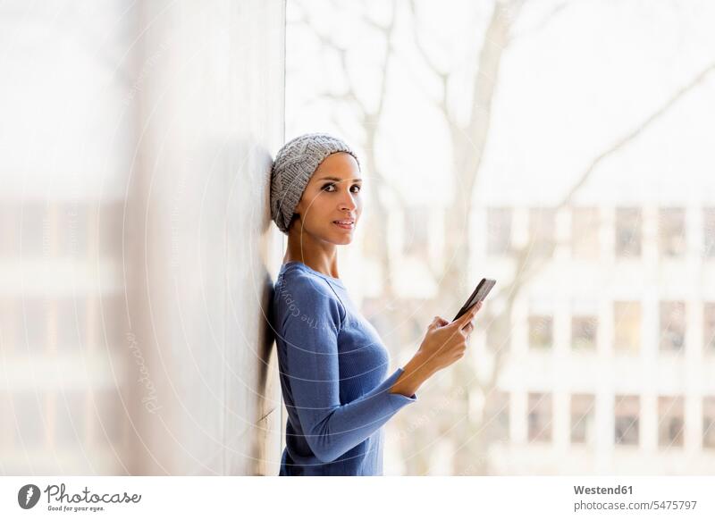 Porträt einer jungen Frau mit Handy vor dem Fenster Portrait Porträts Portraits Smartphone iPhone Smartphones weiblich Frauen Mobiltelefon Handies Handys