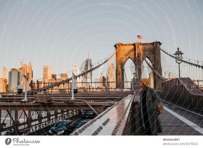 USA, New York, New York City, weiblicher Tourist auf Brooklyn Bridge im Morgenlicht Touristin morgendliches Licht Reisende Reisender Frau Frauen morgens früh