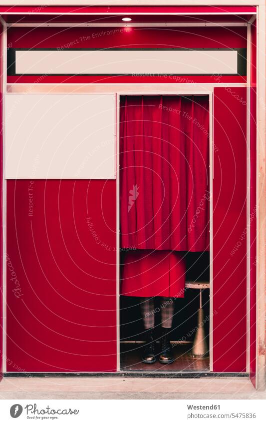 Frau in rotem Mantel und Stiefeln steht hinter einem Vorhang in einer Fotokabine Gardine Gardinen Vorhänge Schuhe Farben Farbtoene Farbton Farbtöne roter rotes
