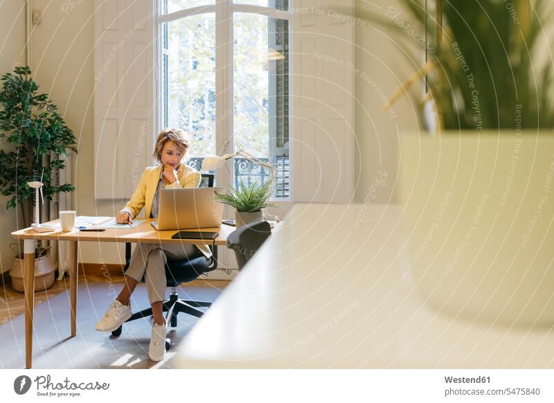 Ingenieurin, die am Laptop arbeitet, während sie im Büro sitzt Farbaufnahme Farbe Farbfoto Farbphoto Innenaufnahme Innenaufnahmen innen drinnen Tag