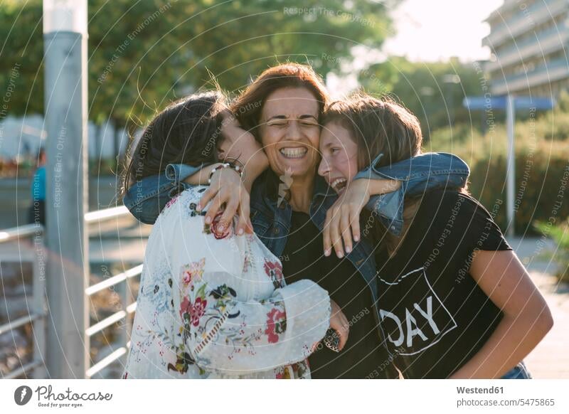 Fröhliche, liebevolle Mutter umarmt Töchter, während sie im Freien steht Farbaufnahme Farbe Farbfoto Farbphoto Portugal Freizeitbeschäftigung Muße Zeit