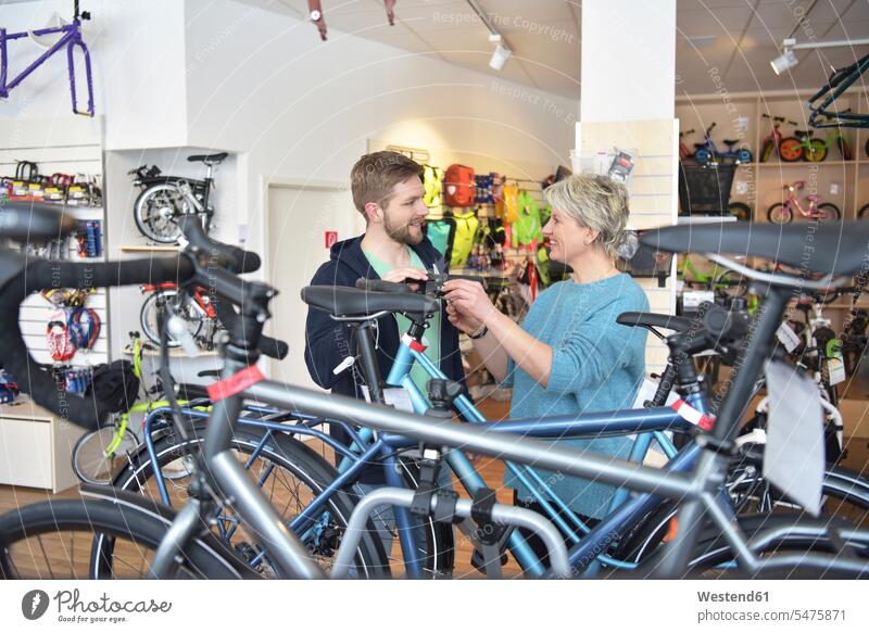Verkäufer hilft Kunde im Fahrradgeschäft Fachverkäufer Fahrradmechaniker Geschäft Shop Laden Läden Geschäfte Shops Kundin Beratung verkaufen Bikes Fahrräder