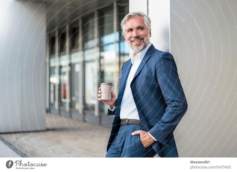 Lächelnder reifer Geschäftsmann mit Kaffee zum Mitnehmen in der Stadt Leute Menschen People Person Personen Europäisch Kaukasier kaukasisch 1 Ein ein Mensch