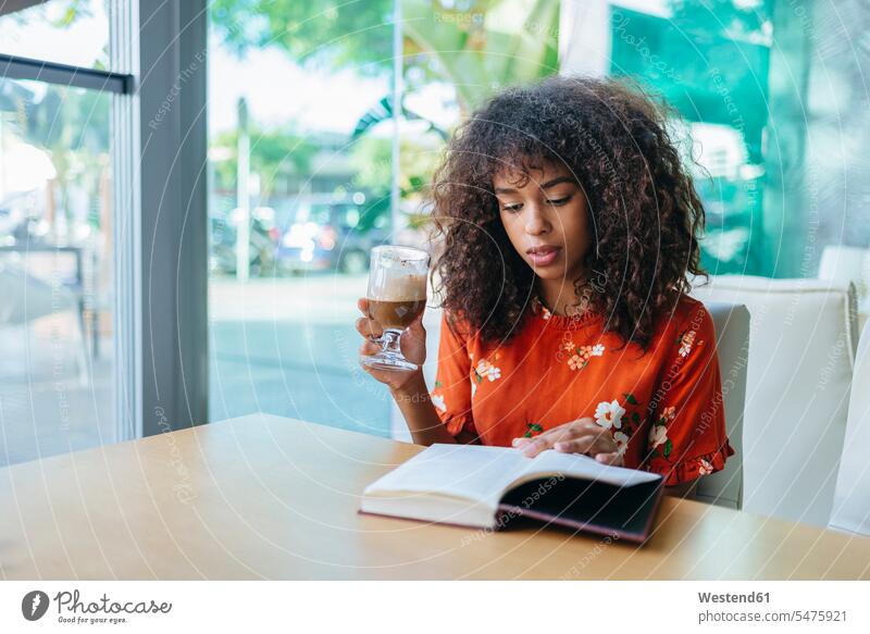 Porträt einer jungen Frau, die in einem Café Kaffee trinkt und ein Buch liest trinken Bücher Portrait Porträts Portraits lesen Lektüre Cafe Kaffeehaus Bistro
