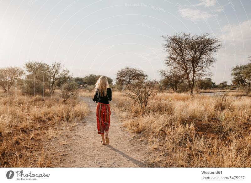 Afrika, Namibia, blonde Frau geht auf Weg in Grasland gehen gehend weiblich Frauen Rückansicht Rueckansicht Rückenansicht Rueckenansicht von hinten Reisende