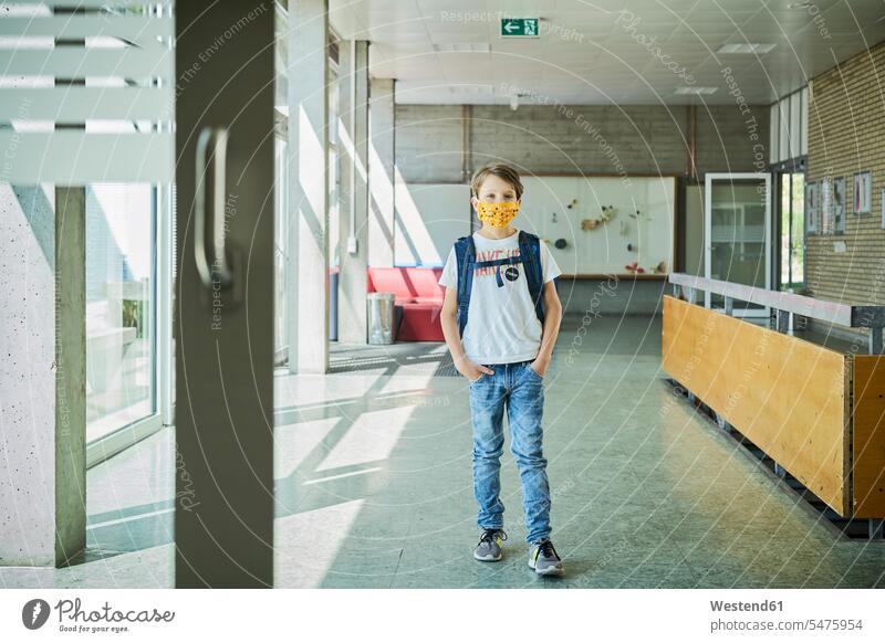 Junge mit Maske in der Schule Ausbildung Schueler Schulkinder Schüler Rucksäcke T-Shirts stehend steht Gesund geschützt schützen Absicherung Schulen Flure Gang