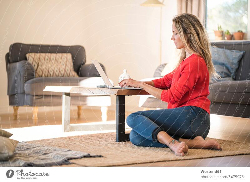 Frau mit Laptop auf Couchtisch zu Hause Zuhause daheim Couchtische Notebook Laptops Notebooks Boden Böden Boeden weiblich Frauen Tisch Tische Computer Rechner