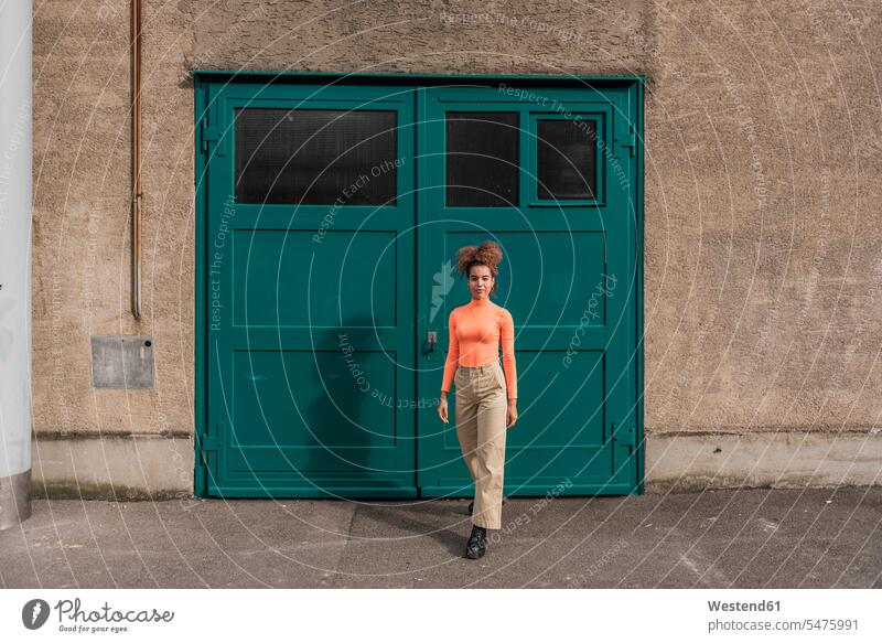 Junge Frau geht gegen grüne Tür Farbaufnahme Farbe Farbfoto Farbphoto Außenaufnahme außen draußen im Freien Tag Tageslichtaufnahme Tageslichtaufnahmen