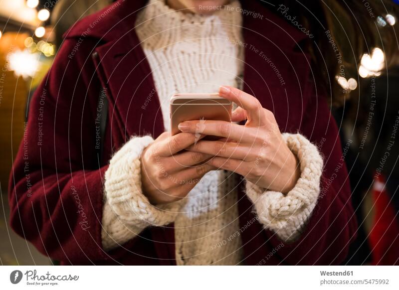Hände einer jungen Frau, die ein Smartphone hält, Nahaufnahme Informationen Telekommunikation Handies Handys Mobiltelefon Mobiltelefone abends Farben Farbtoene