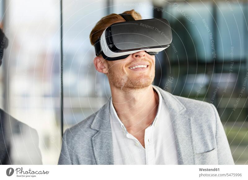 Lächelnder Geschäftsmann mit VR-Brille lächeln virtuell Virtualität Brillen Businessmann Businessmänner Geschäftsmänner rothaarig rote Haare rothaarige
