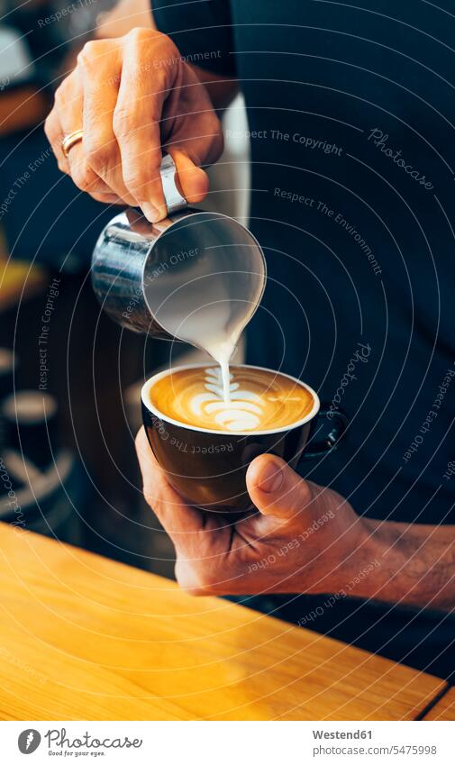 Nahaufnahme eines Barista bei der Zubereitung von Cappuccino in einem Coffee-Shop Baristas Cappucino Cafe Kaffeehaus Bistro Cafes Café Cafés Kaffeehäuser