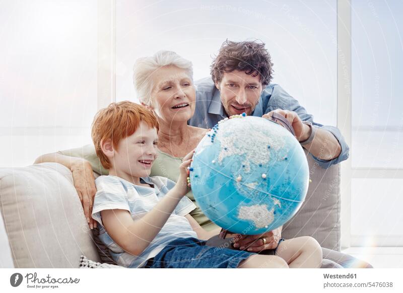 Grossmutter, Vater und Enkel sitzen auf einer Couch in einer Villa und schauen auf den Globus Generation Erdkugel Globen Weltkugel Couches Liege Sofas sitzend